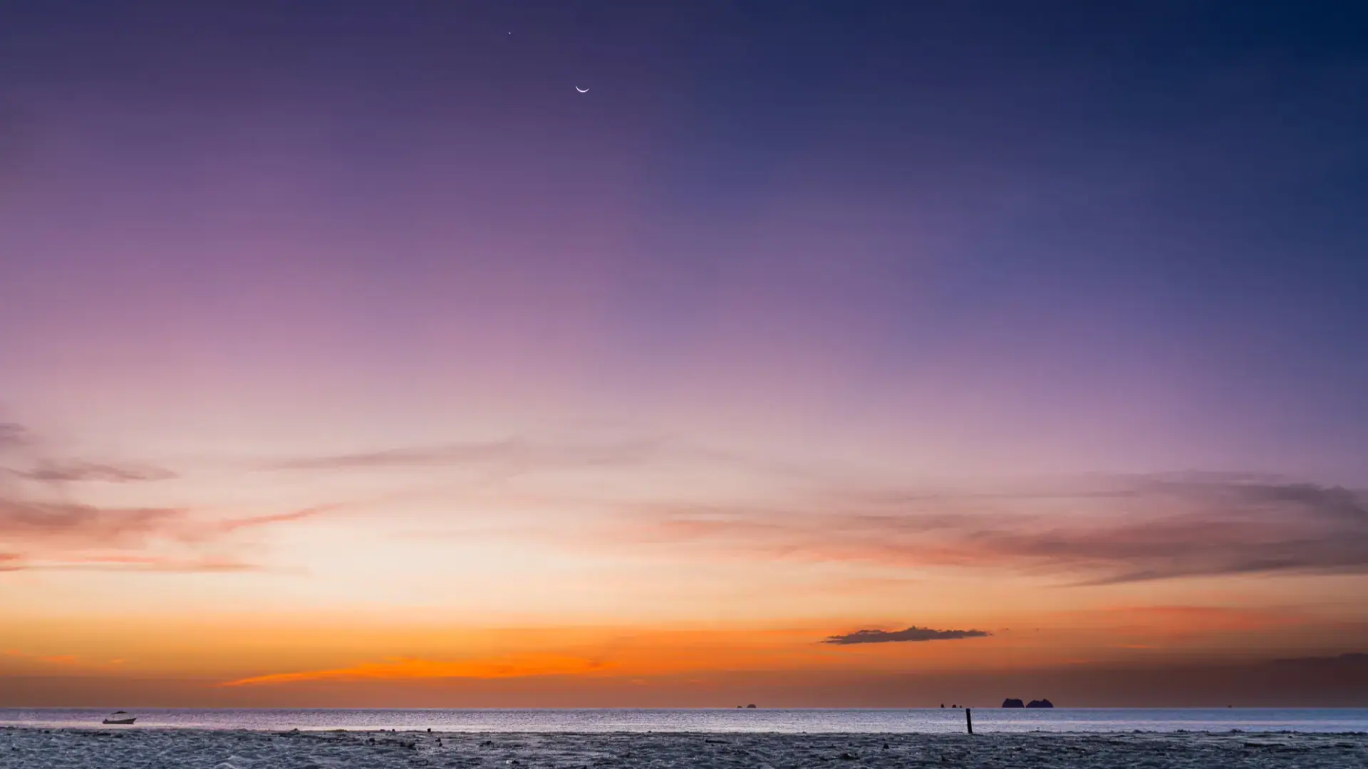 Golden Pacific sunset with crescent moon over the beach